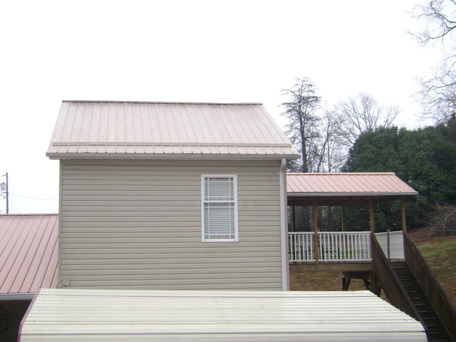 Tan metal roofs on a two story addition and attached porch, from a Roof Replacement job in Marysville